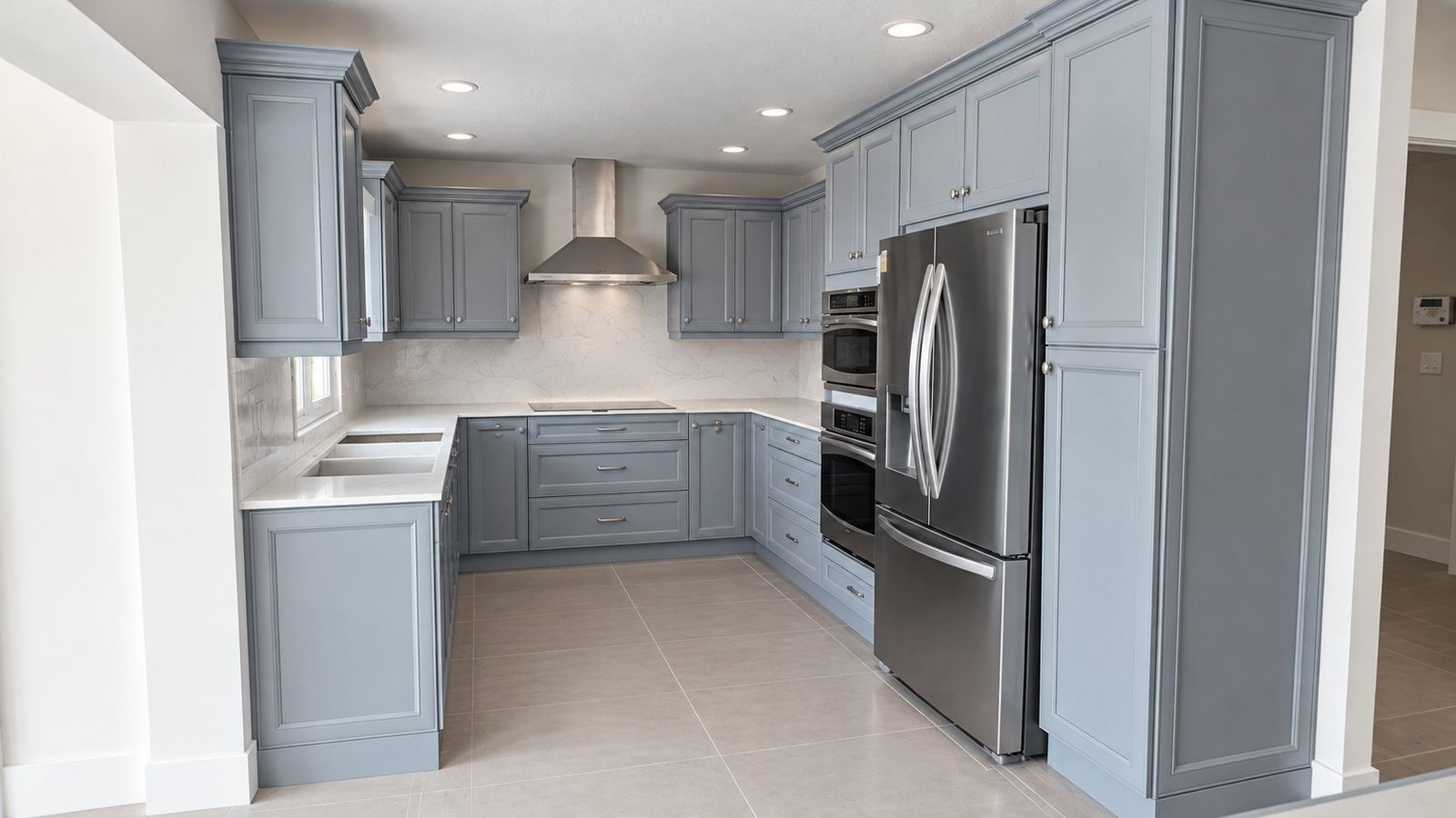 U-shaped kitchen with blue-gray painted cabinets, white countertops and stainless steel appliances