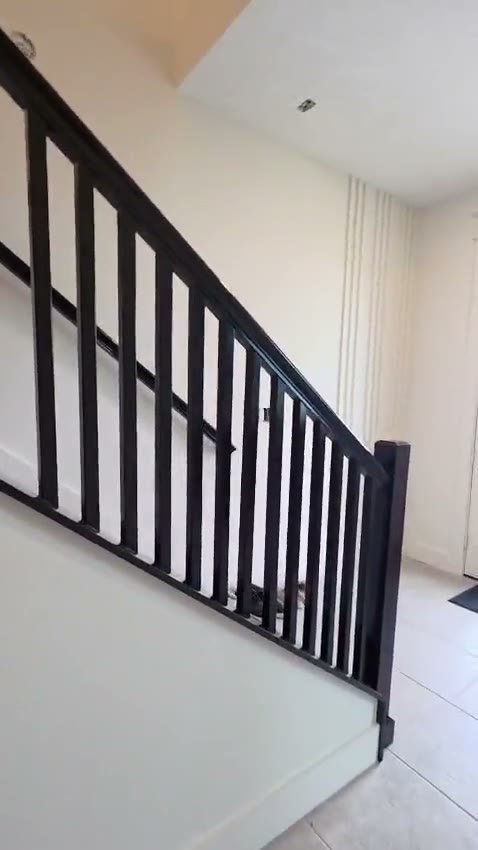 Video of a staircase with a dark railing and balusters before painting